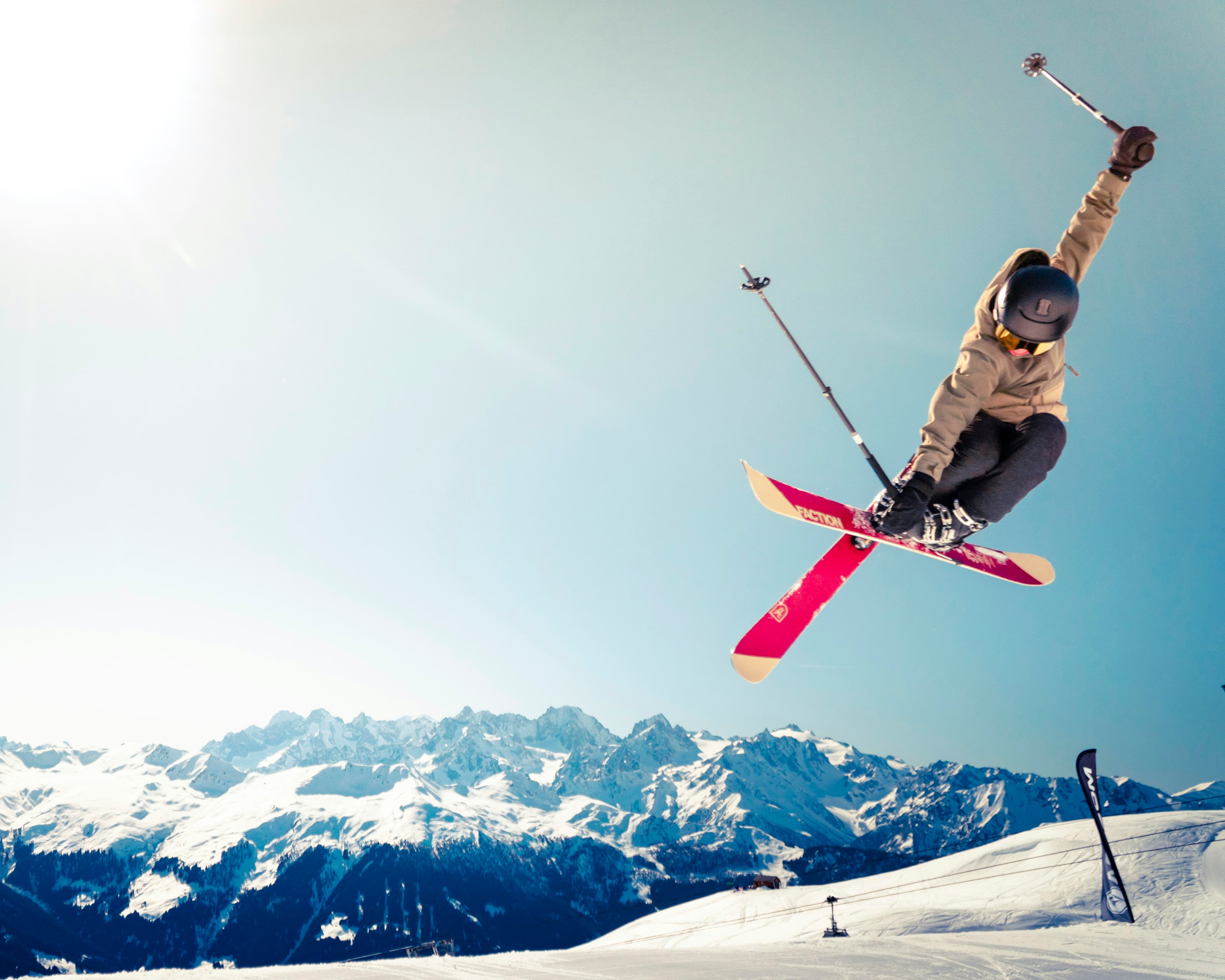 A skier in mid-air above snowy peaks