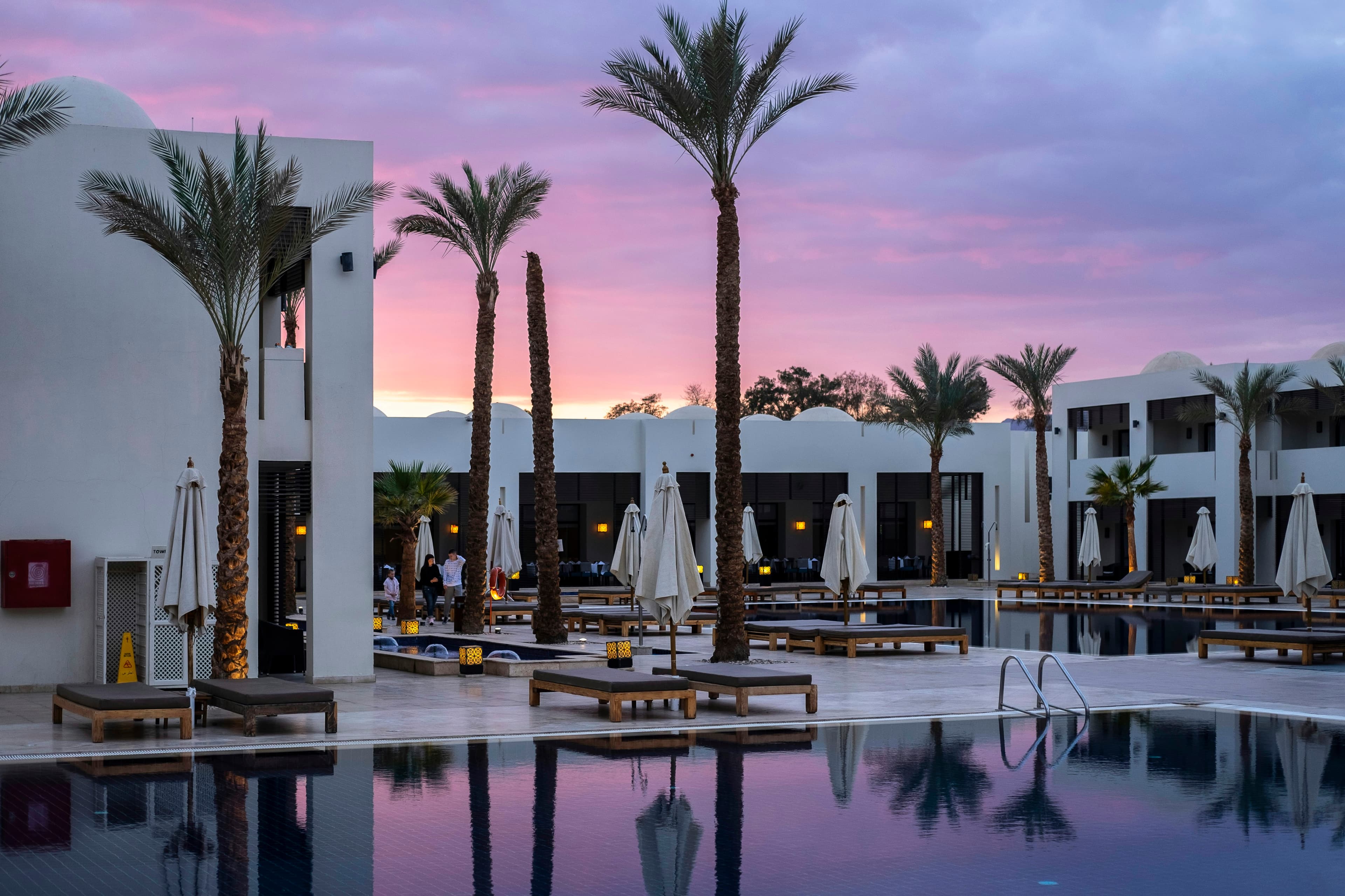 Palms and a long pool at dusk under a desert sky