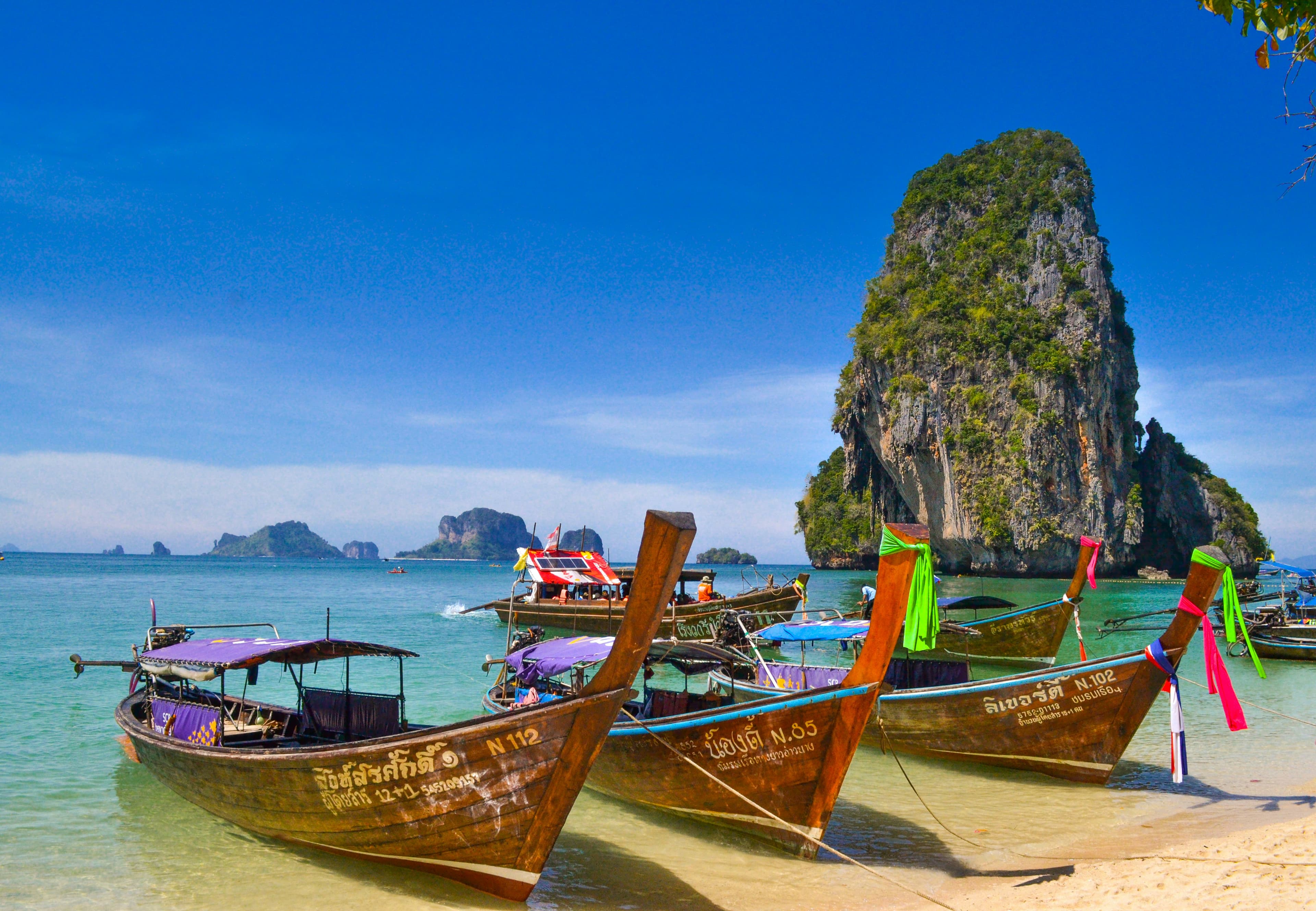 Longtail boats beneath a limestone karst in Krabi