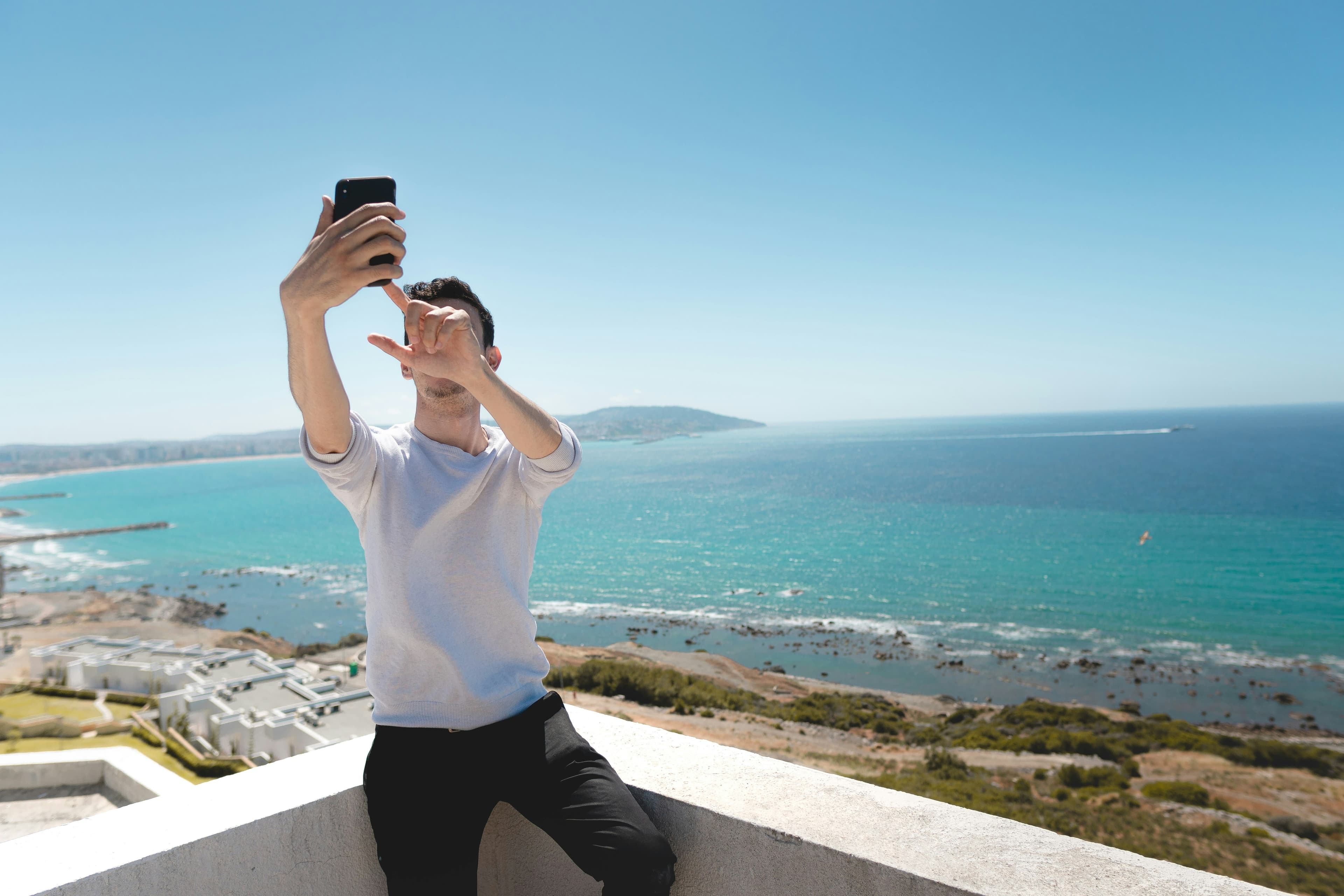 A man taking a selfie on a balcony overlooking the sea