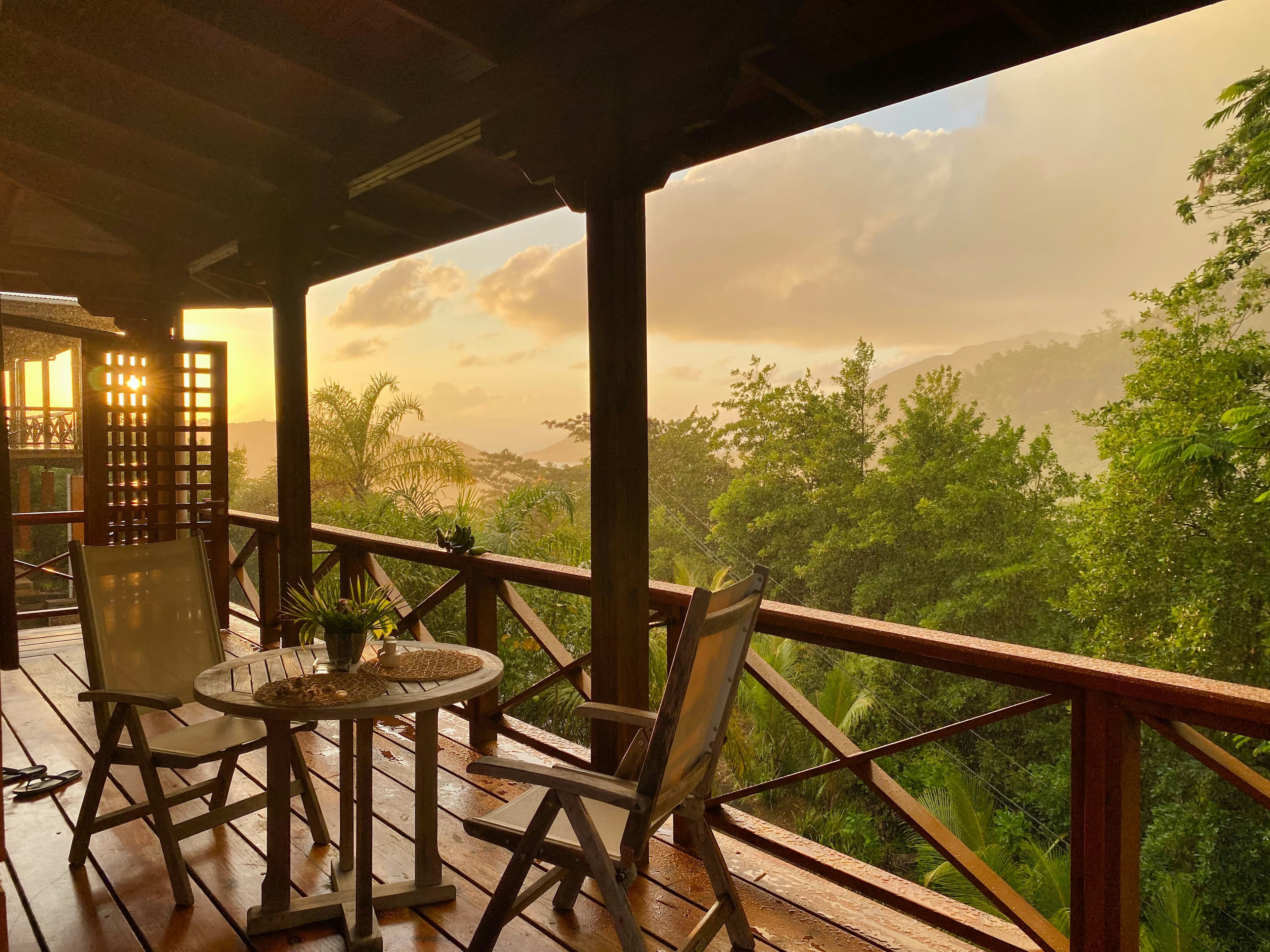 A timber balcony overlooking jungle at sunset