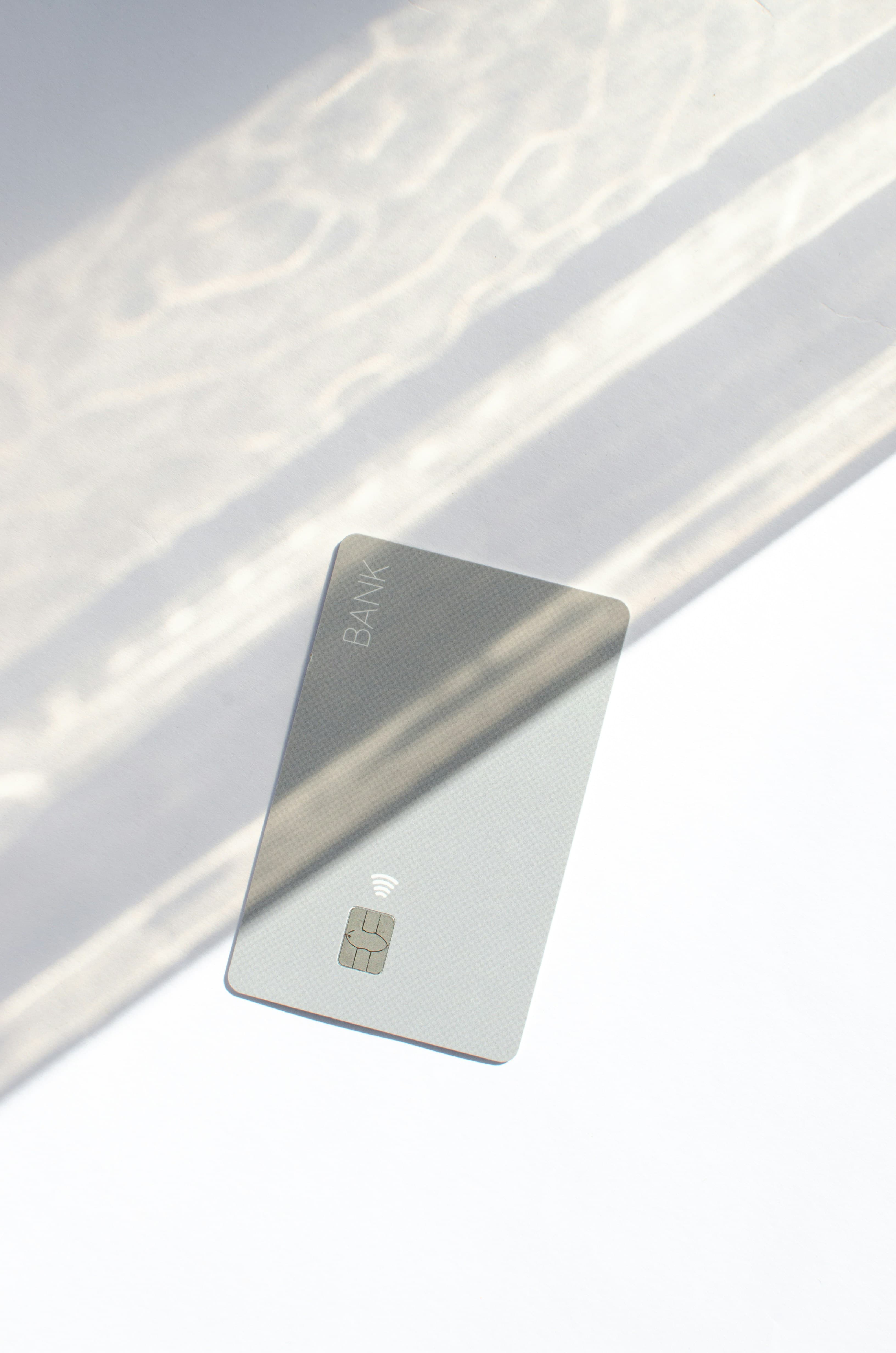 A silver bank card resting in soft light on a pale surface