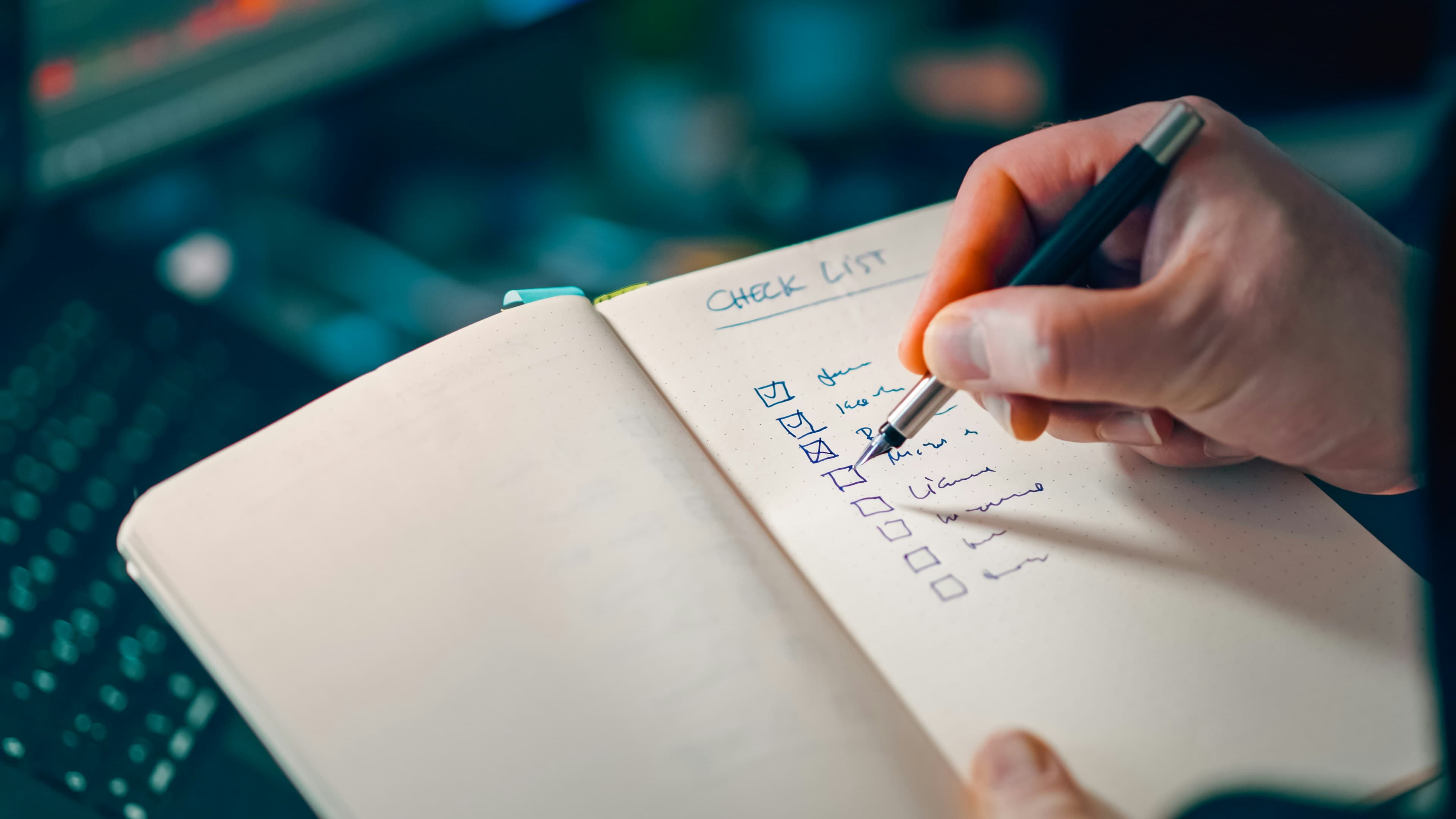 A hand writing a checklist in an open notebook