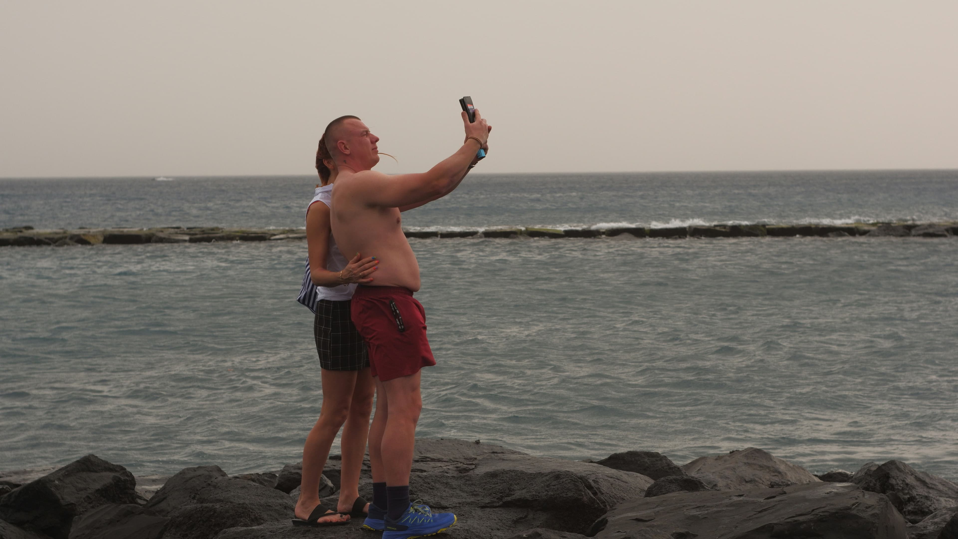 A couple taking a selfie on a rocky beach